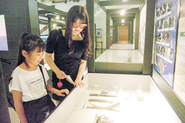クジラのひげの工芸品を楽しむ来館者