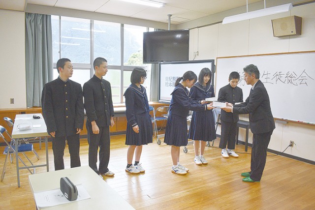 村上事務長（右端）が生徒たちに絵本を贈呈
